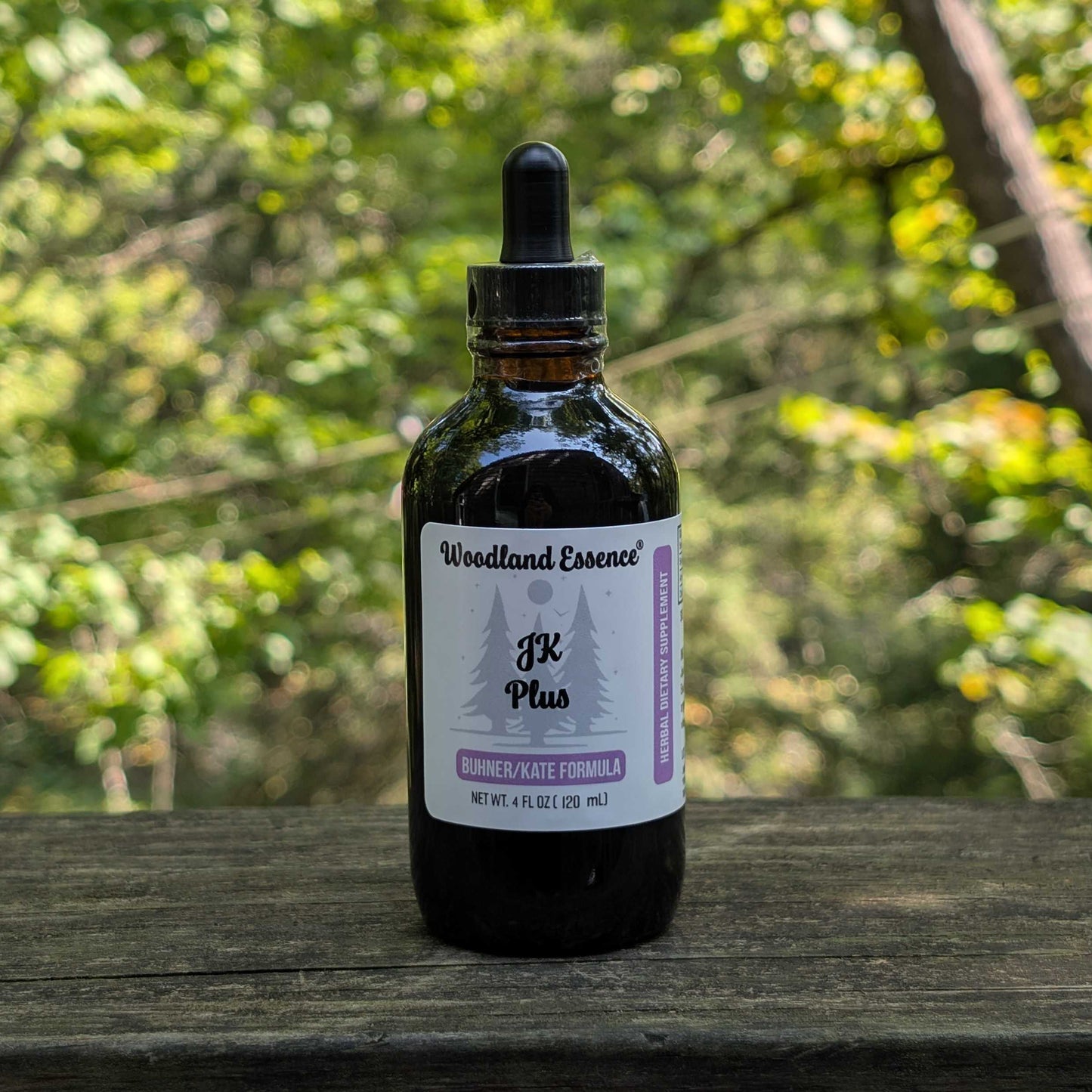 Bottle of Woodland Essence JK Plus on a wooden surface with a blurred green forest background