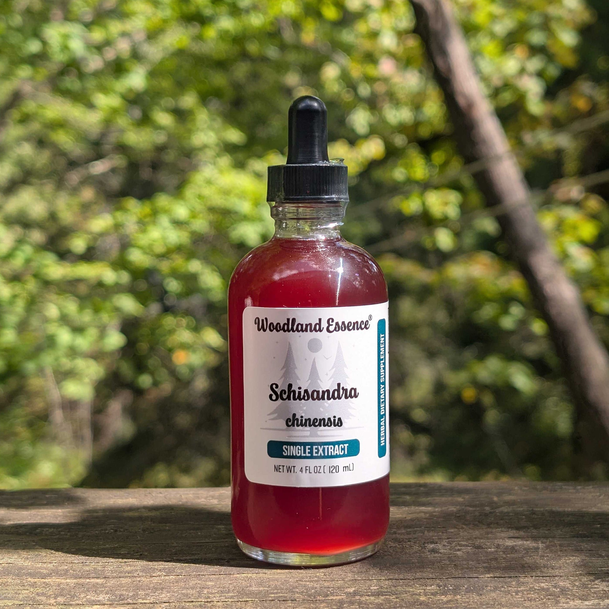 Bottle of Woodland Essence Schisandra chinensis extract on a wooden surface with a blurred green background