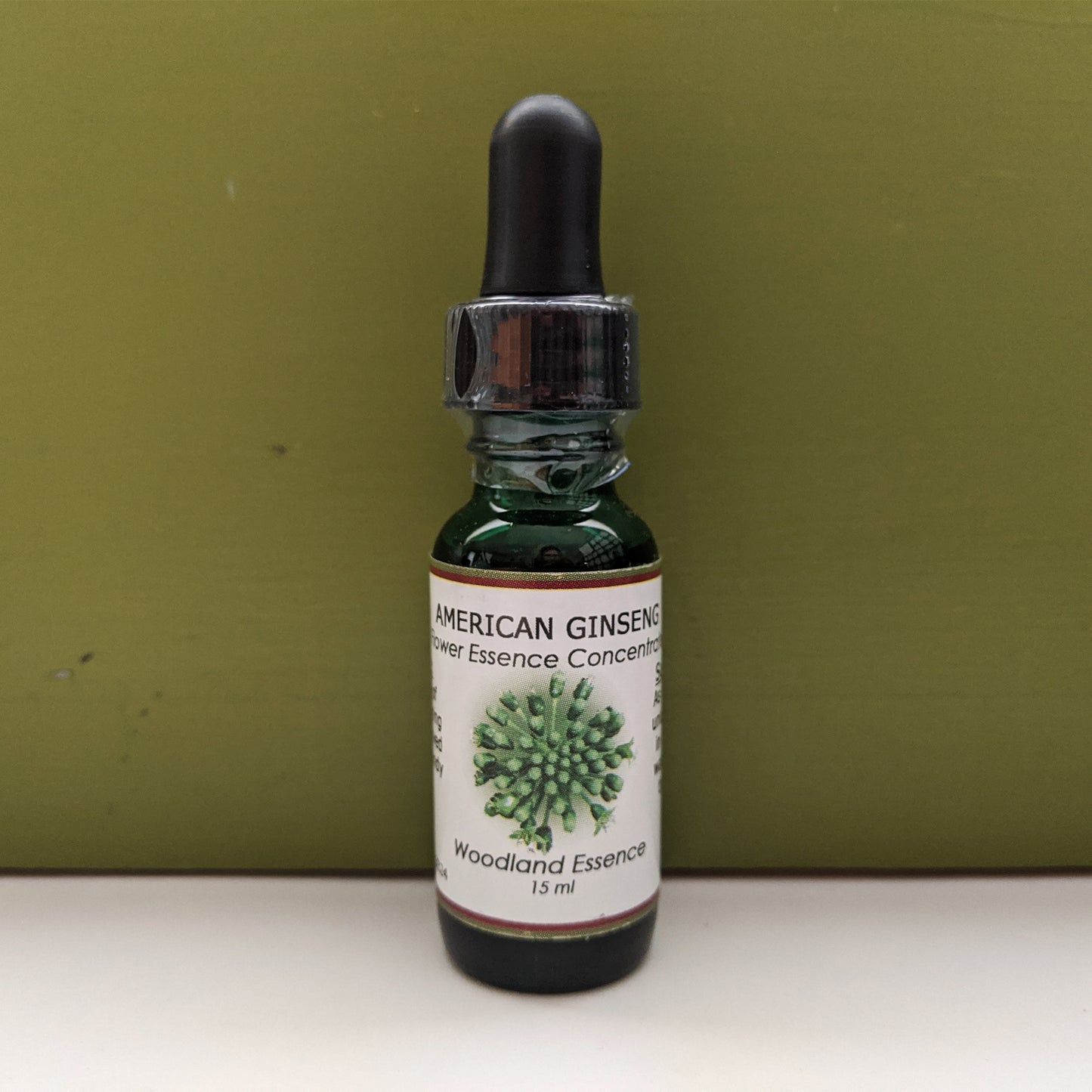 American Ginseng Flower Essence bottle against green back drop
