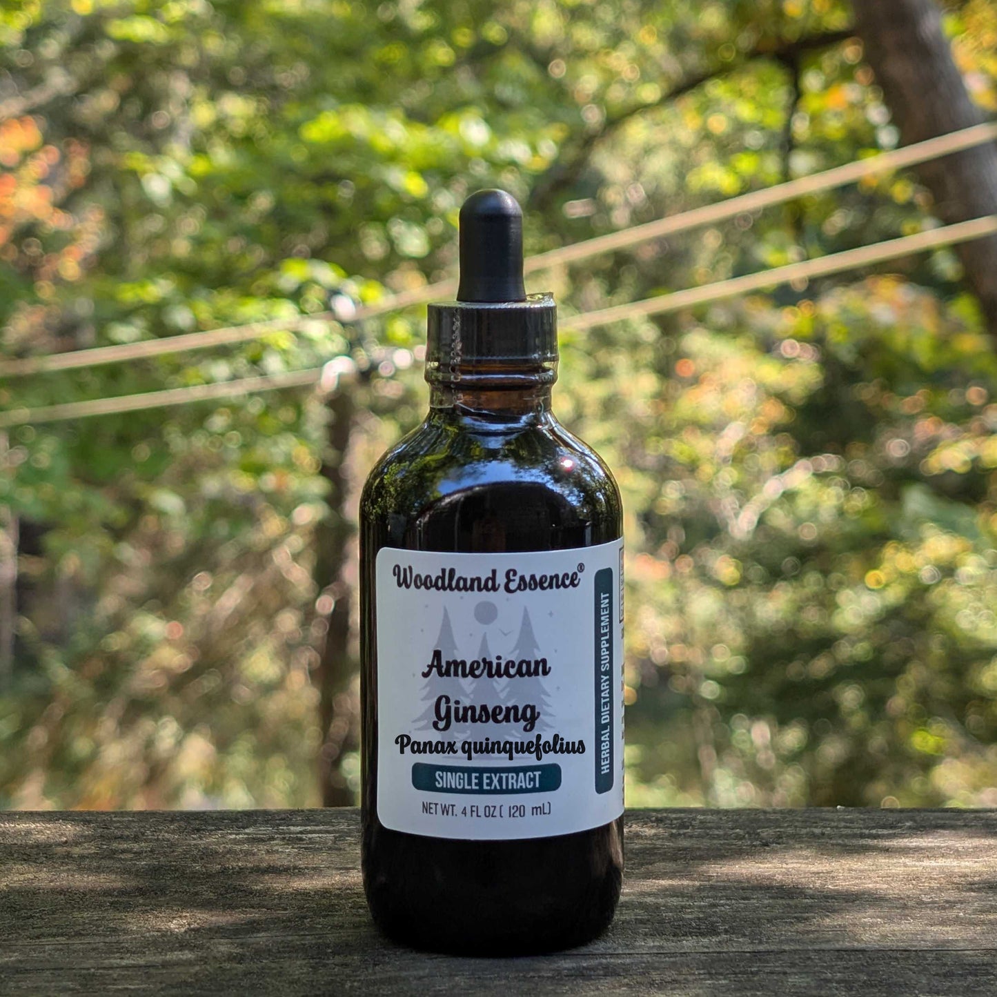 Bottle of Woodland Essence American Ginseng extract on a wooden surface with a forest background