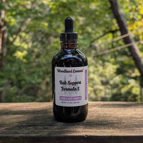 Bottle of Woodland Essence Bab Support Formula 2 on a wooden surface with a blurred natural background