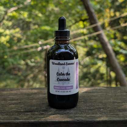 Bottle of Woodland Essence Calm the Cascade on a wooden surface with a blurred natural background