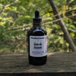 Bottle of Woodland Essence Calm the Cascade on a wooden surface with a blurred natural background