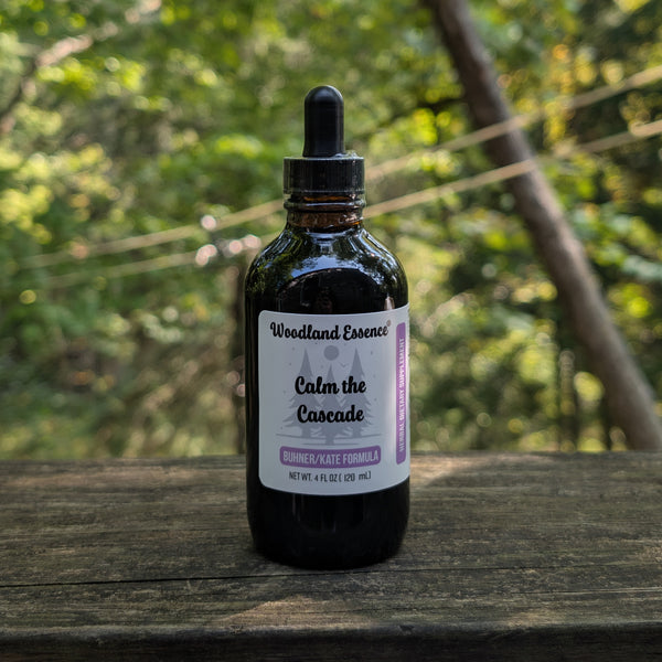 Bottle of Woodland Essence Calm the Cascade on a wooden surface with a blurred natural background