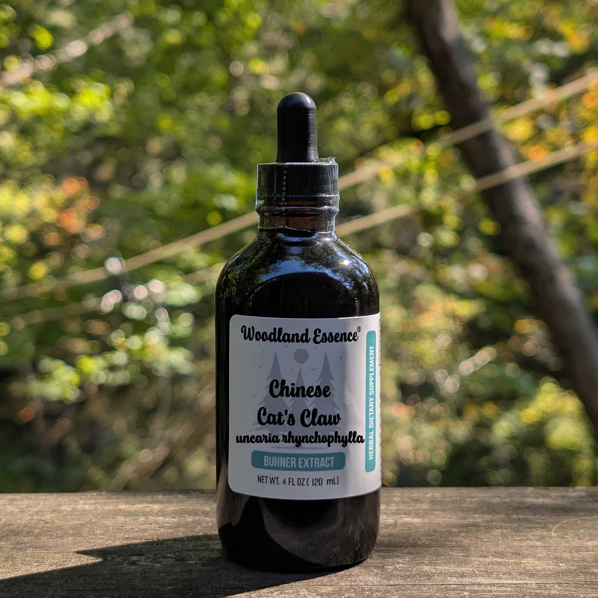 Bottle of Woodland Essence Chinese Cat's Claw Extract on a wooden surface with a natural background