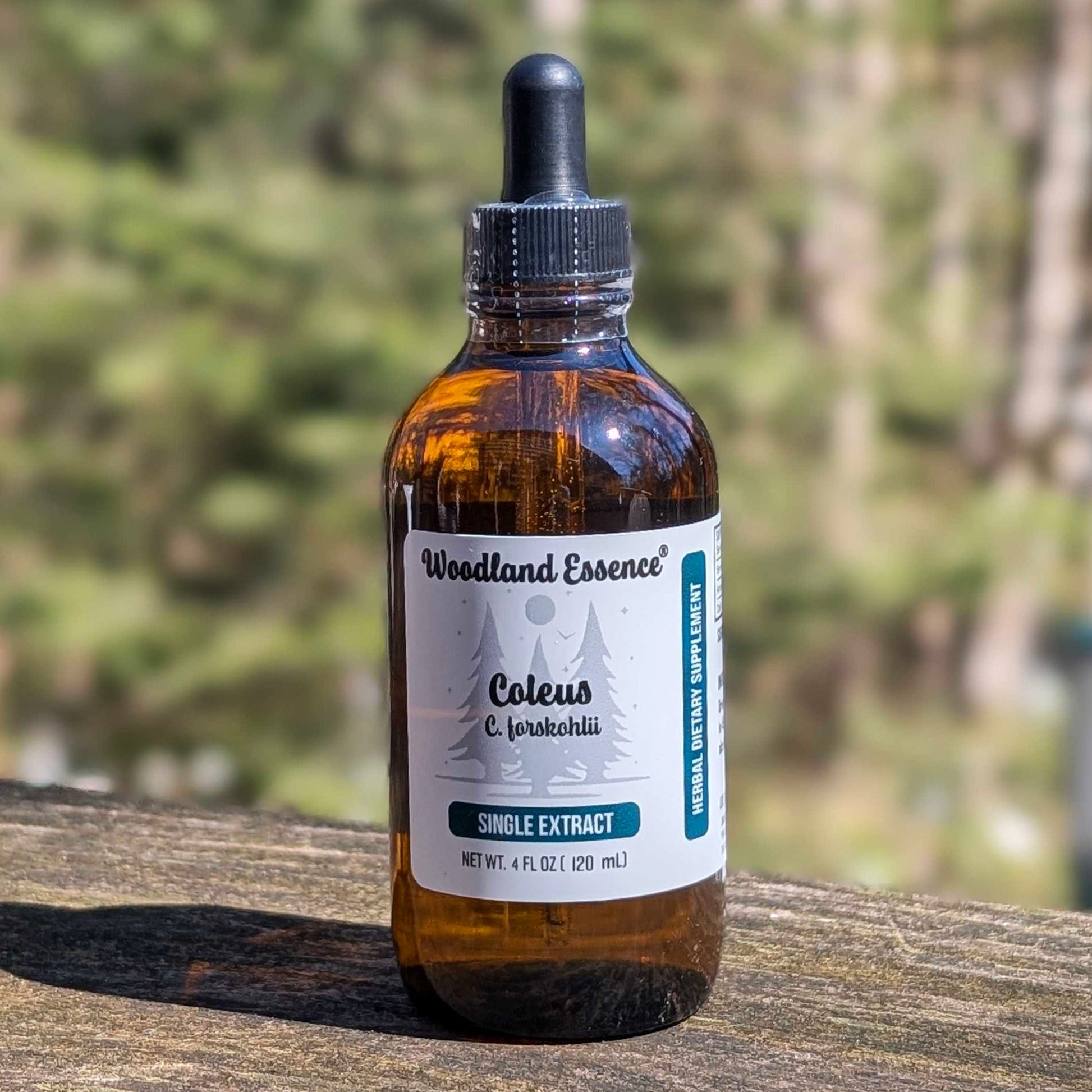 Bottle of Woodland Essence Coleus extract on a wooden surface with a blurred natural background