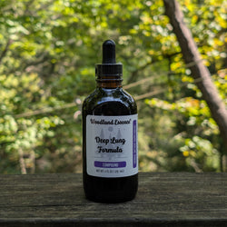 Bottle of 'Woodland Essence Deep Lung Formula' on a wooden surface with a blurred natural background