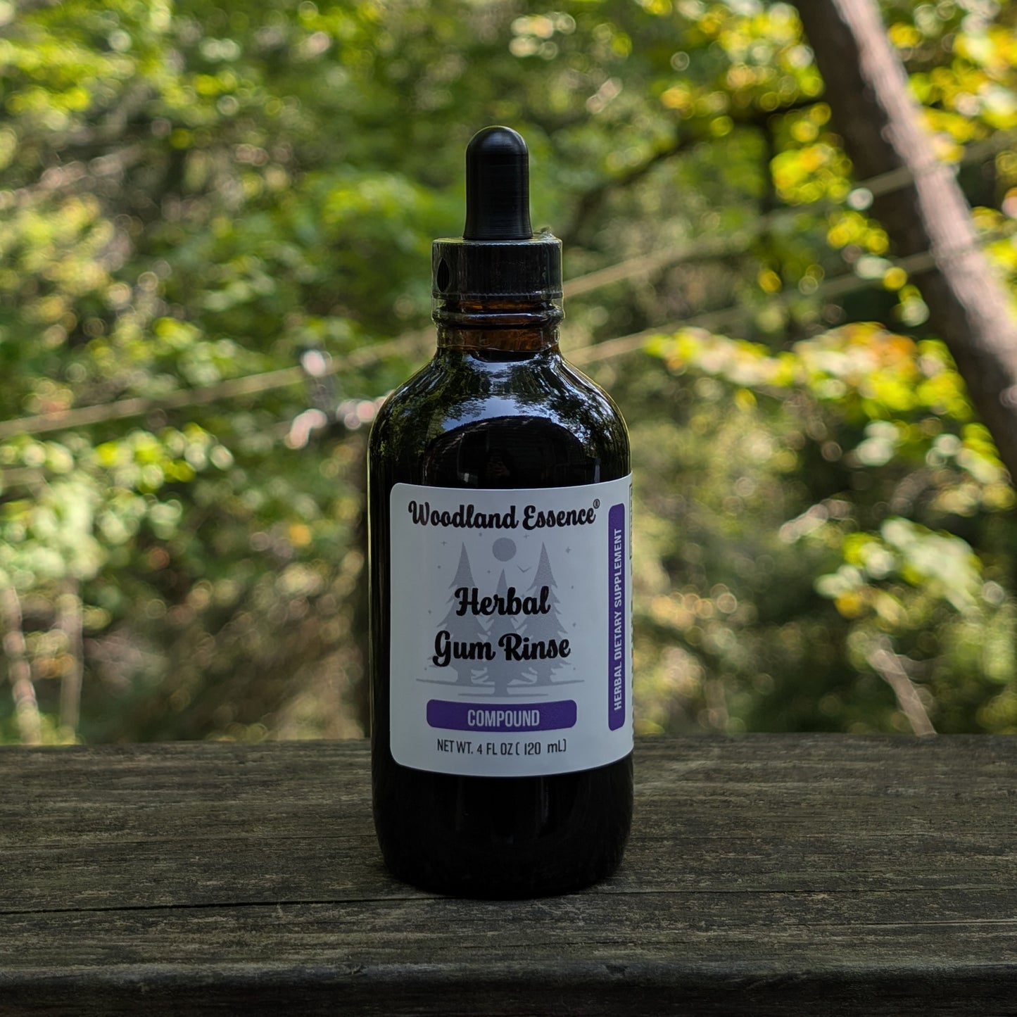 Bottle of Woodland Essence Herbal Gum Rinse on a wooden surface with a blurred natural background