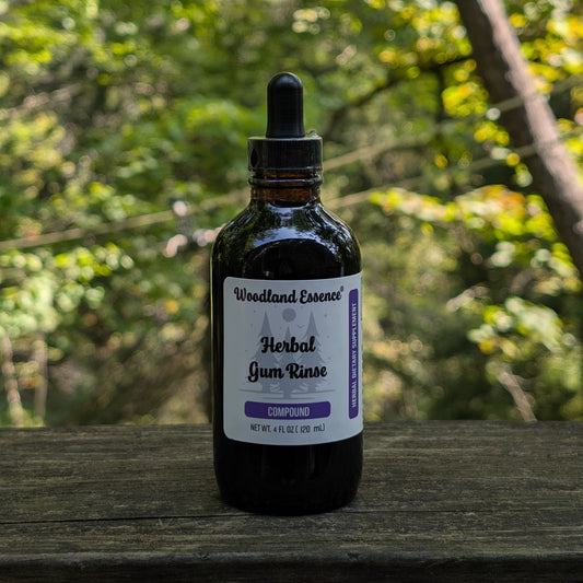 Bottle of Woodland Essence Herbal Gum Rinse on a wooden surface with a blurred natural background