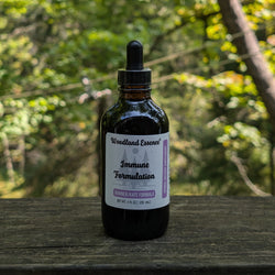 Bottle of Woodland Essence Immune Formulation on a wooden surface with a natural background