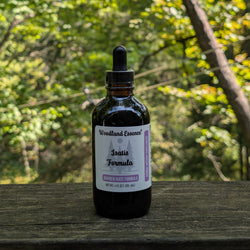 Bottle of Woodland Essence Isatis Formula on a wooden surface with a blurred natural background