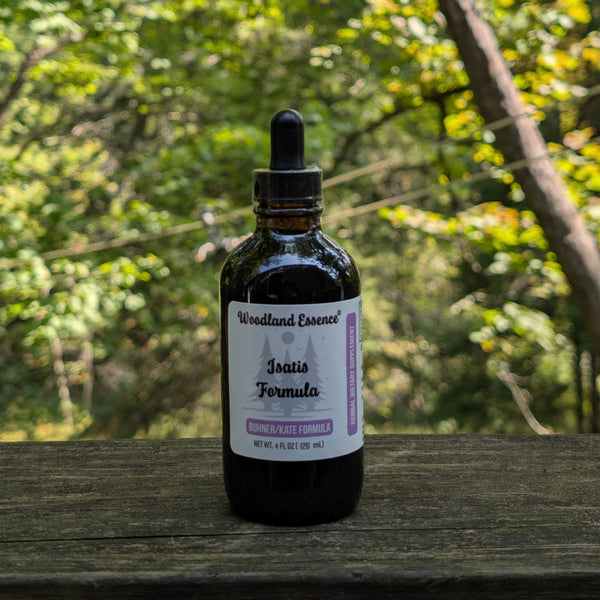 Bottle of Woodland Essence Isatis Formula on a wooden surface with a blurred natural background