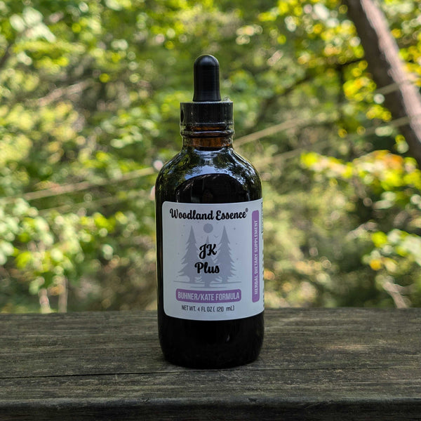 Bottle of Woodland Essence JK Plus on a wooden surface with a blurred green forest background