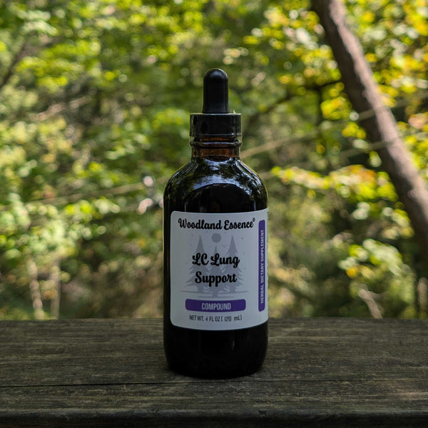 Bottle of Woodland Essence LC Lung Support on a wooden surface with a blurred green forest background