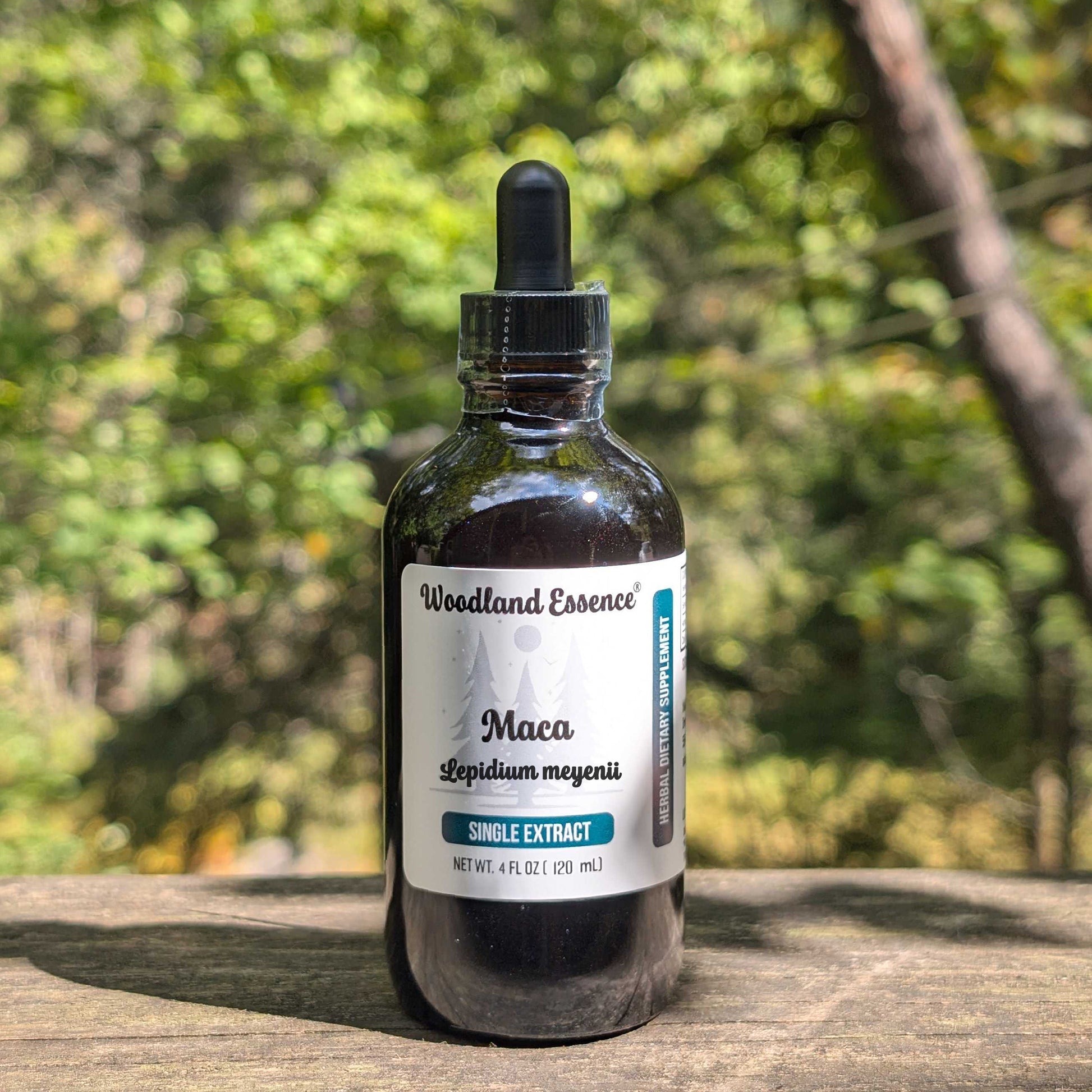 Bottle of Woodland Essence Maca extract on a wooden surface with a blurred natural background