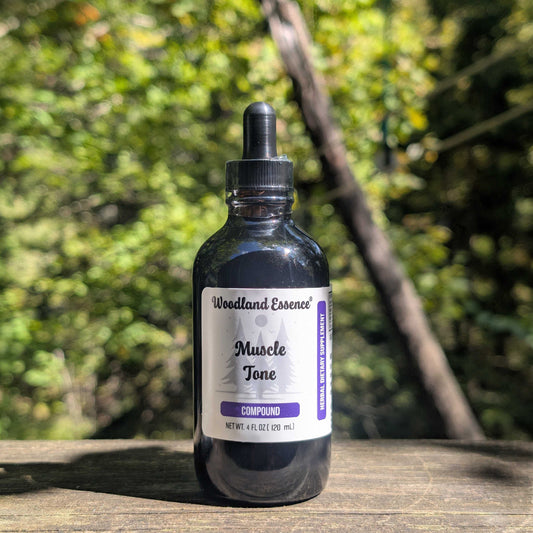 Bottle of Woodland Essence Muscle Tone Compound on a wooden surface with a blurred natural background