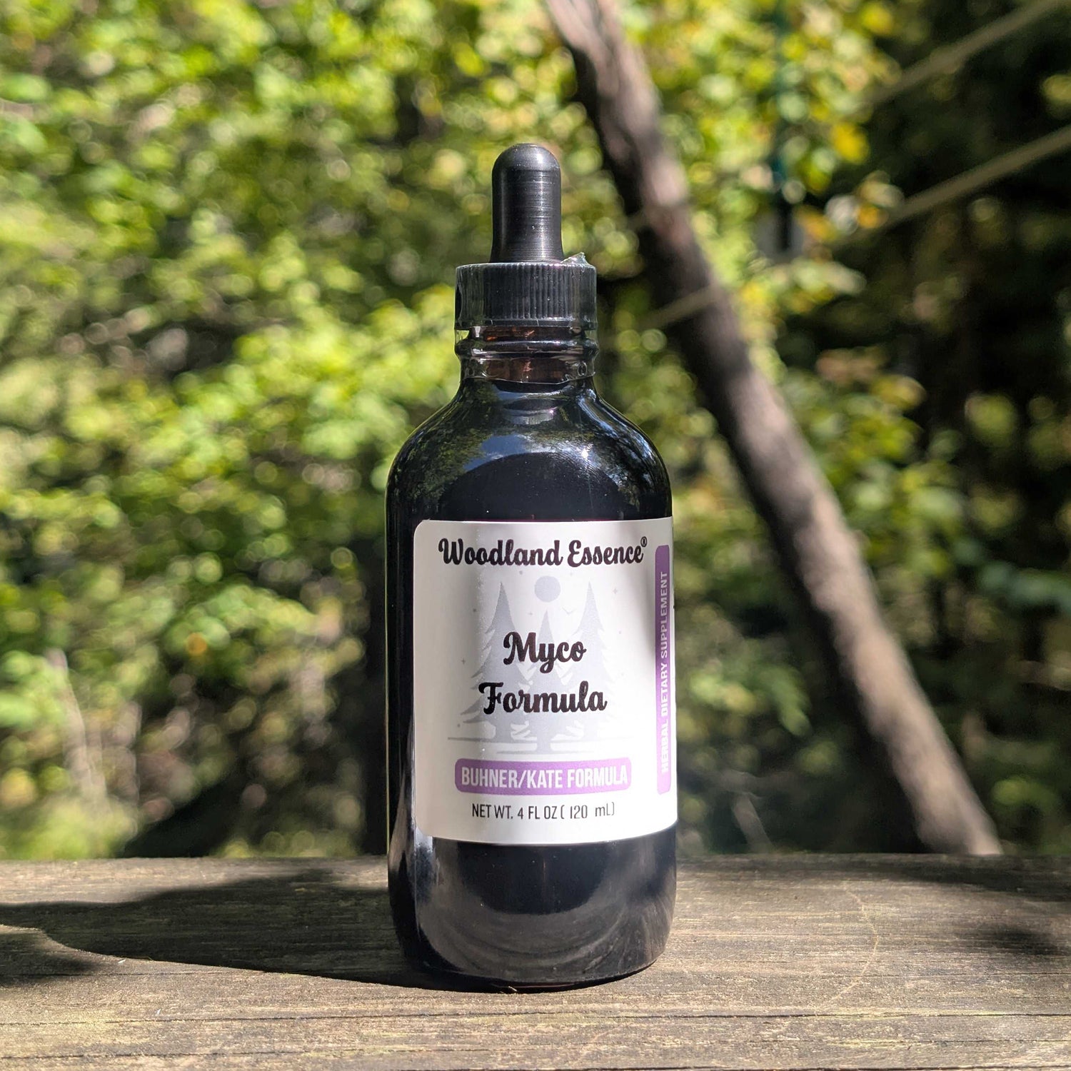 Bottle of Woodland Essence Myco Formula on a wooden surface with a blurred natural background