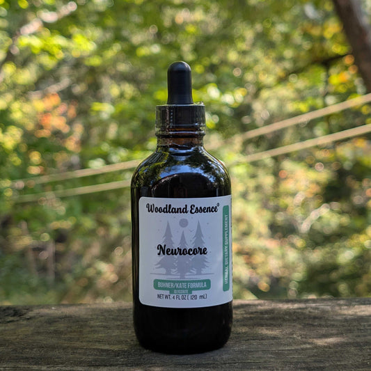 Bottle of Woodland Essence Neurocore tincture with a dropper on a wooden surface with a blurred natural background.