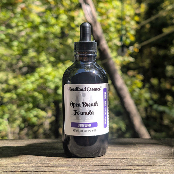 Bottle of Woodland Essence Open Breath Formula Compound on a wooden surface with a blurred natural background