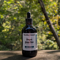 Bottle of Woodland Essence Oregon Grape Root extract on a wooden surface with a blurred natural background