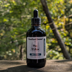 Bottle of Woodland Essence Pau D'Arco extract on a wooden surface with a blurred natural background