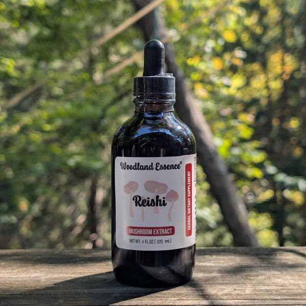Bottle of Woodland Essence Reishi mushroom extract on a wooden surface with a forest background