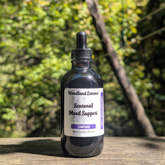Bottle of 'Woodland Essence Seasonal Mood Support' on a wooden surface with a blurred natural background
