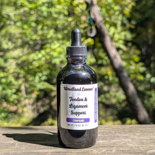 Bottle of Woodland Essence Tendon & Ligament Support Compound on a wooden surface with a blurred natural background