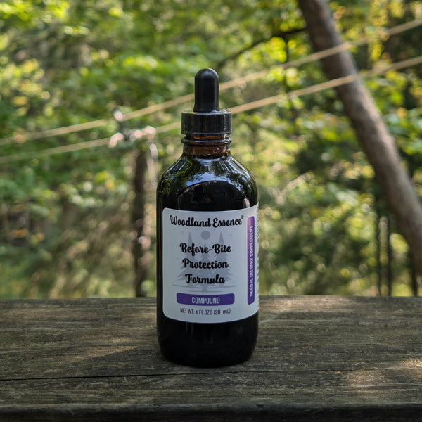 Bottle of Woodland Essence Before Bite Protection Formula on a wooden surface with a blurred natural background