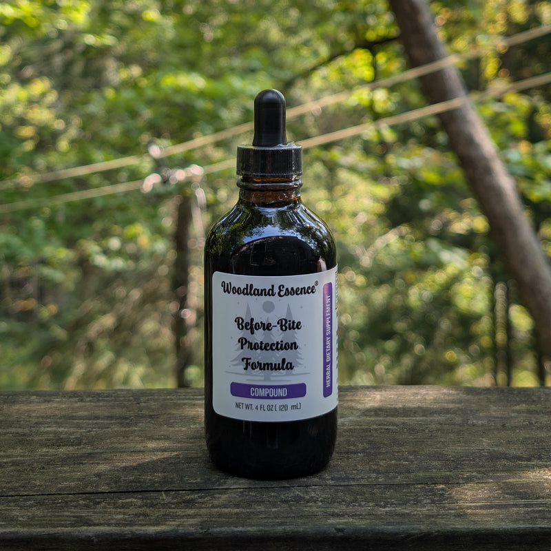 Bottle of Woodland Essence Before Bite Protection Formula on a wooden surface with a blurred natural background