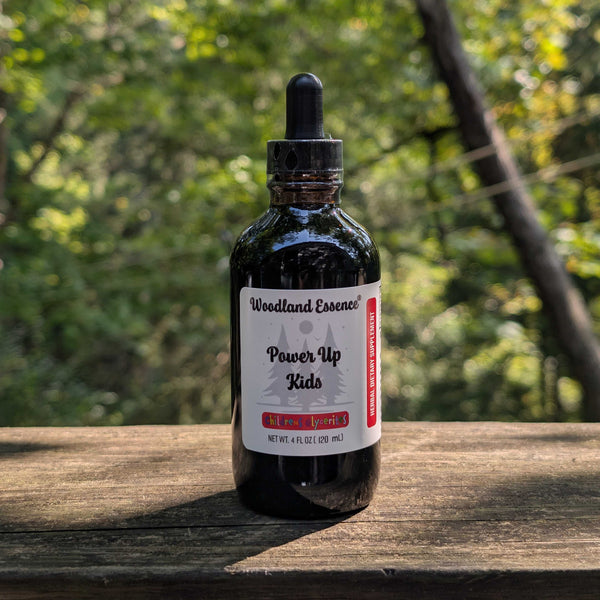 Bottle of Woodland Essence Power Up Kids supplement on a wooden surface with a natural background