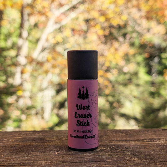 Purple and black bottle labeled 'Wort Eraser Stick' on a wooden surface with a blurred natural background